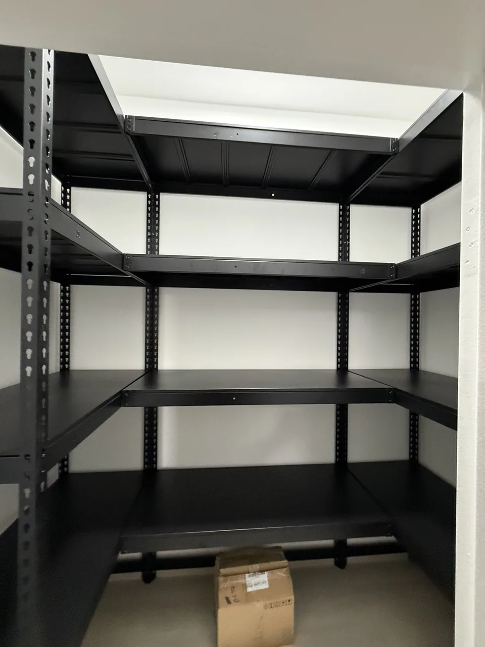Black shelving wrapping three walls of a compact storeroom