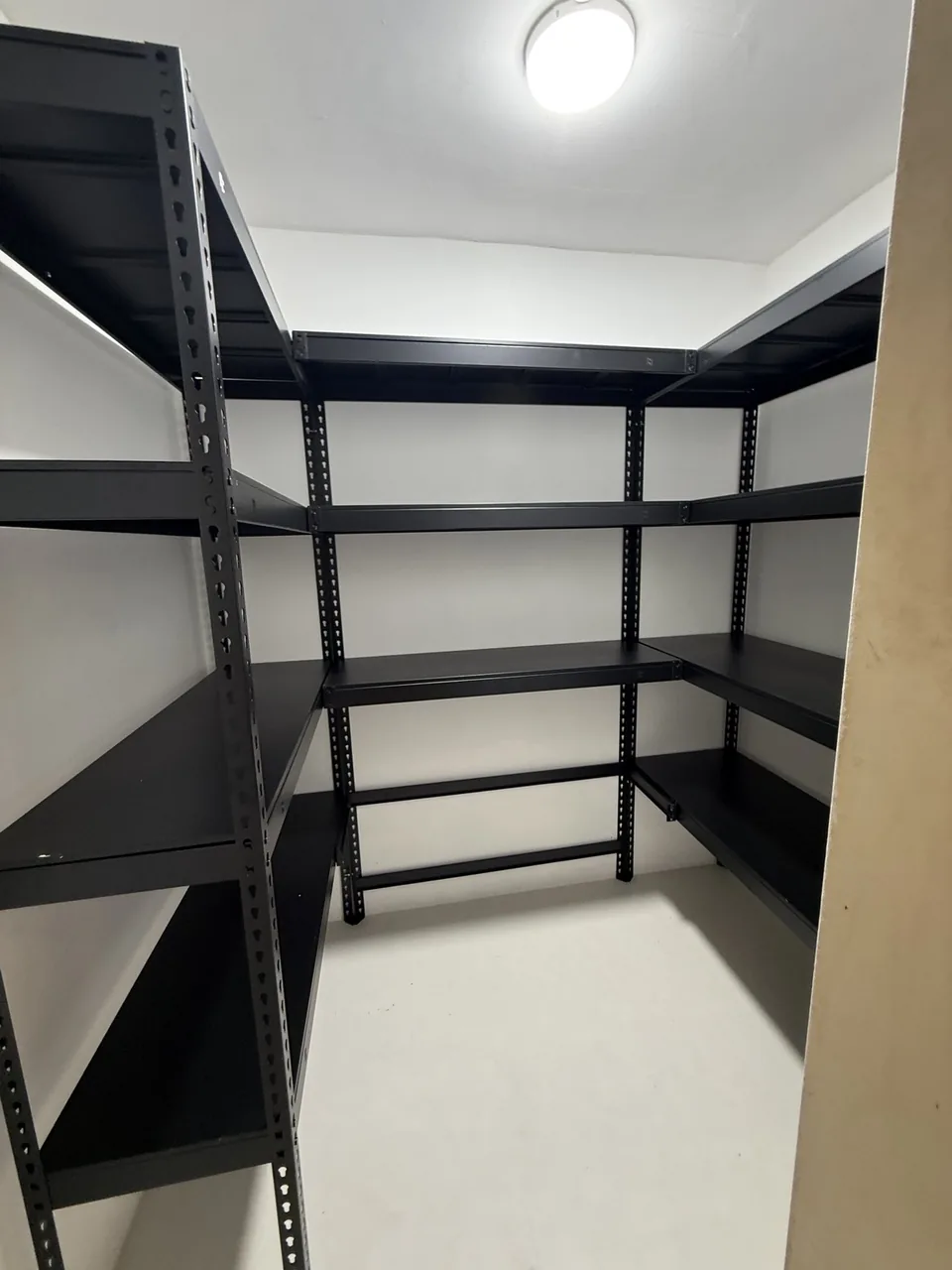 Black shelving wrapping three sides of a compact room