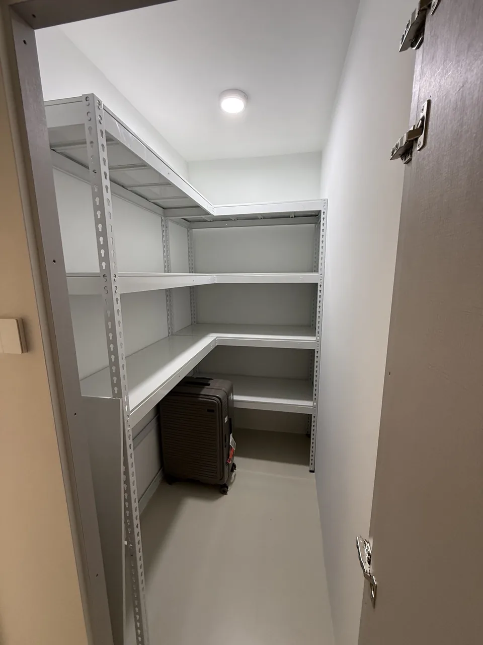 White L-shaped shelves with open space for a suitcase underneath