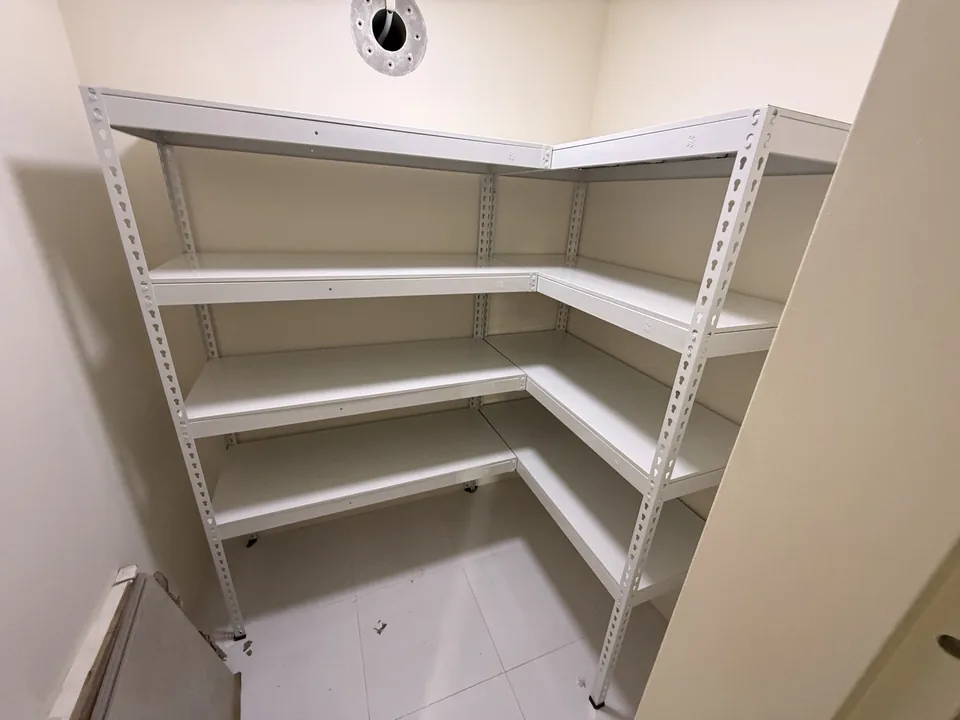 White L-shaped shelves beneath a storeroom ventilation opening