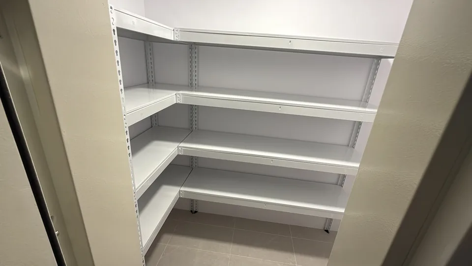 White L-shaped shelving viewed through a narrow doorway