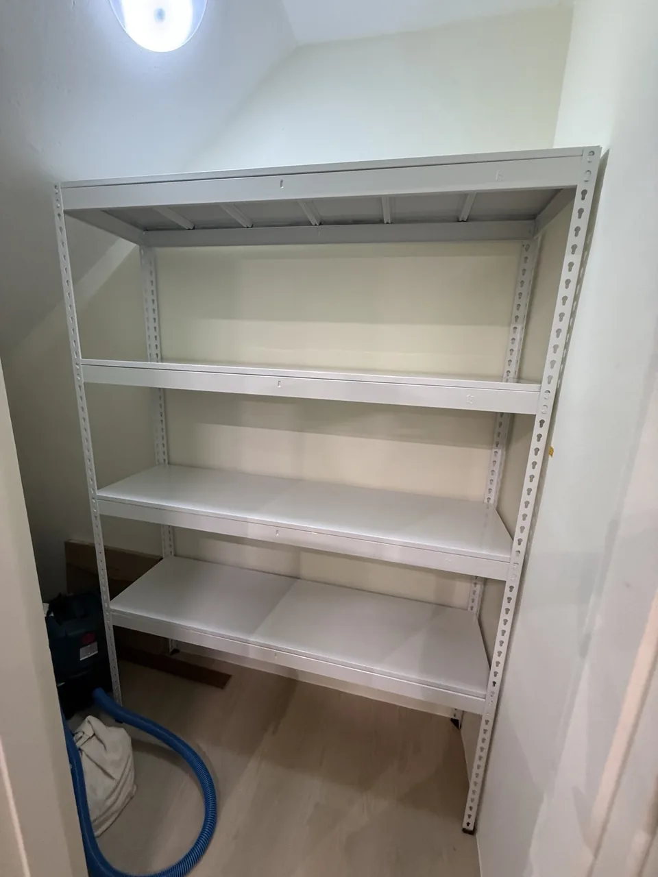 Standalone white four-tier rack in a utility space
