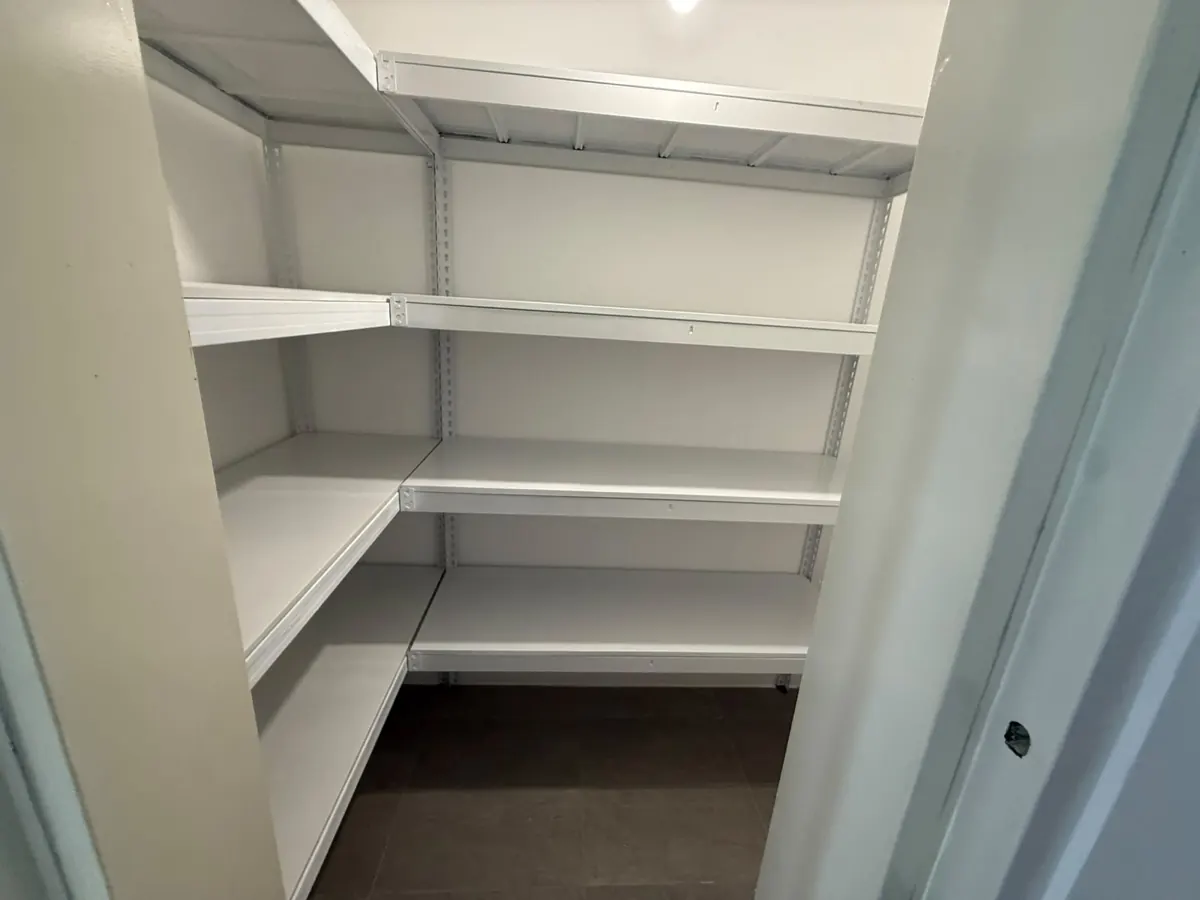 White QH L-shape metal shelving fitted along two storeroom walls